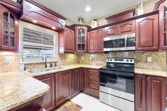 a kitchen with stainless steel appliances kitchen island granite countertop a sink stove and microwave