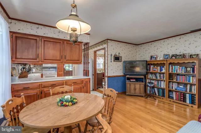 a living room with stainless steel appliances furniture a dining table and a bookshelf