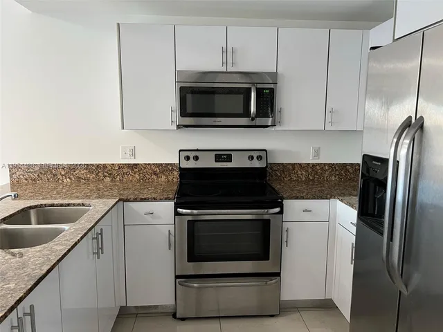 a kitchen with stainless steel appliances granite countertop a sink stove and microwave
