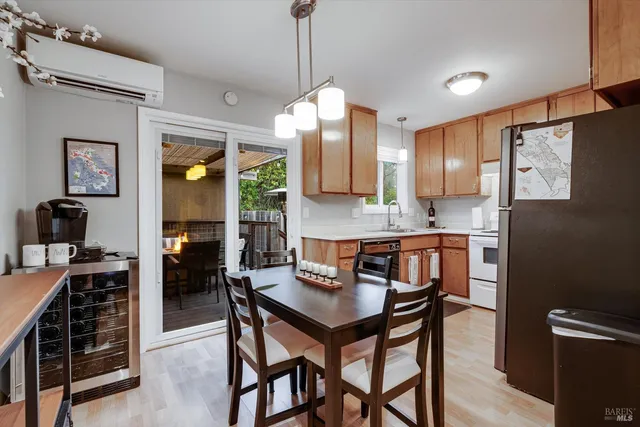 a kitchen with stainless steel appliances granite countertop a stove a refrigerator a sink a dining table and chairs with wooden floor