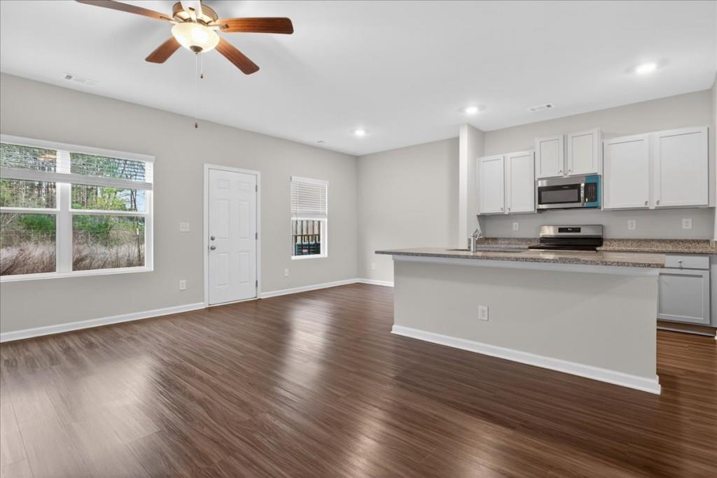 107 Brexley Drive Calhoun, GA 30701 - Photo 3 of 36 a kitchen with stainless steel appliances granite countertop a stove top oven a sink dishwasher and a refrigerator with wooden floors