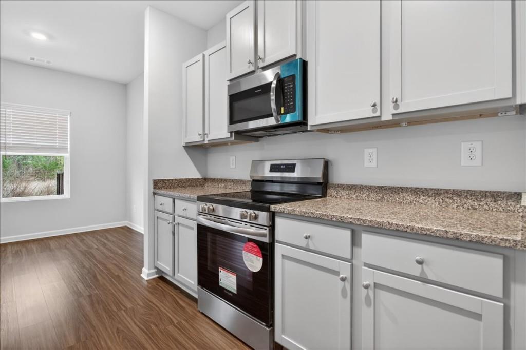 107 Brexley Drive Calhoun, GA 30701 - Photo 7 of 36 a kitchen with stainless steel appliances granite countertop a stove a microwave and wooden cabinets