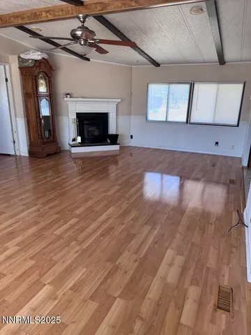 a view of an empty room with wooden floor fireplace and a window