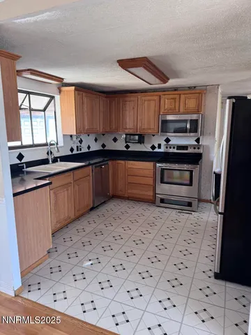 a kitchen with stainless steel appliances a sink a stove a refrigerator and cabinets