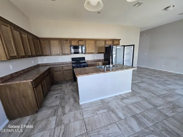 a kitchen with stainless steel appliances a sink a stove top oven a counter space and cabinets