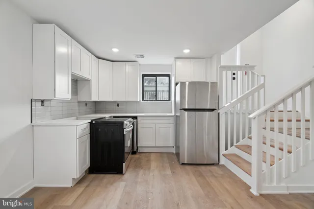 a kitchen with a refrigerator and white cabinets