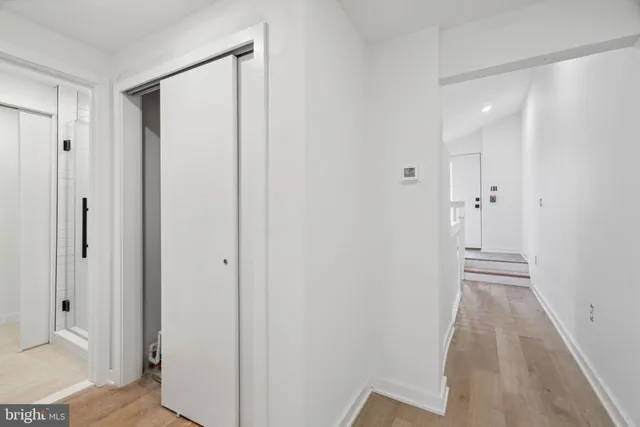 a view of a hallway with wooden floor and a bathroom