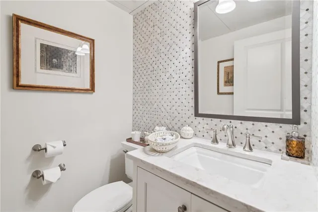 a bathroom with a granite countertop sink mirror and toilet