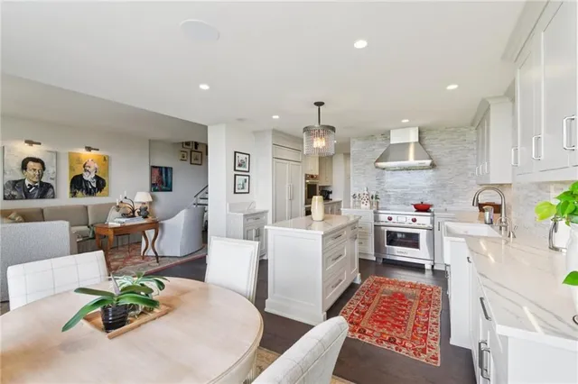 a open kitchen with stainless steel appliances granite countertop a stove a sink dishwasher a dining table and chairs with wooden floor