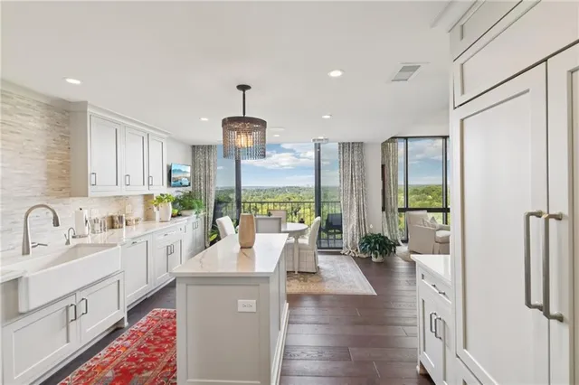 a large kitchen with stainless steel appliances a refrigerator a sink dishwasher a oven and a dining table with wooden floor