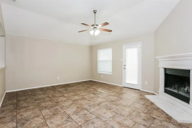 a view of an empty room with chandelier fan and fire place