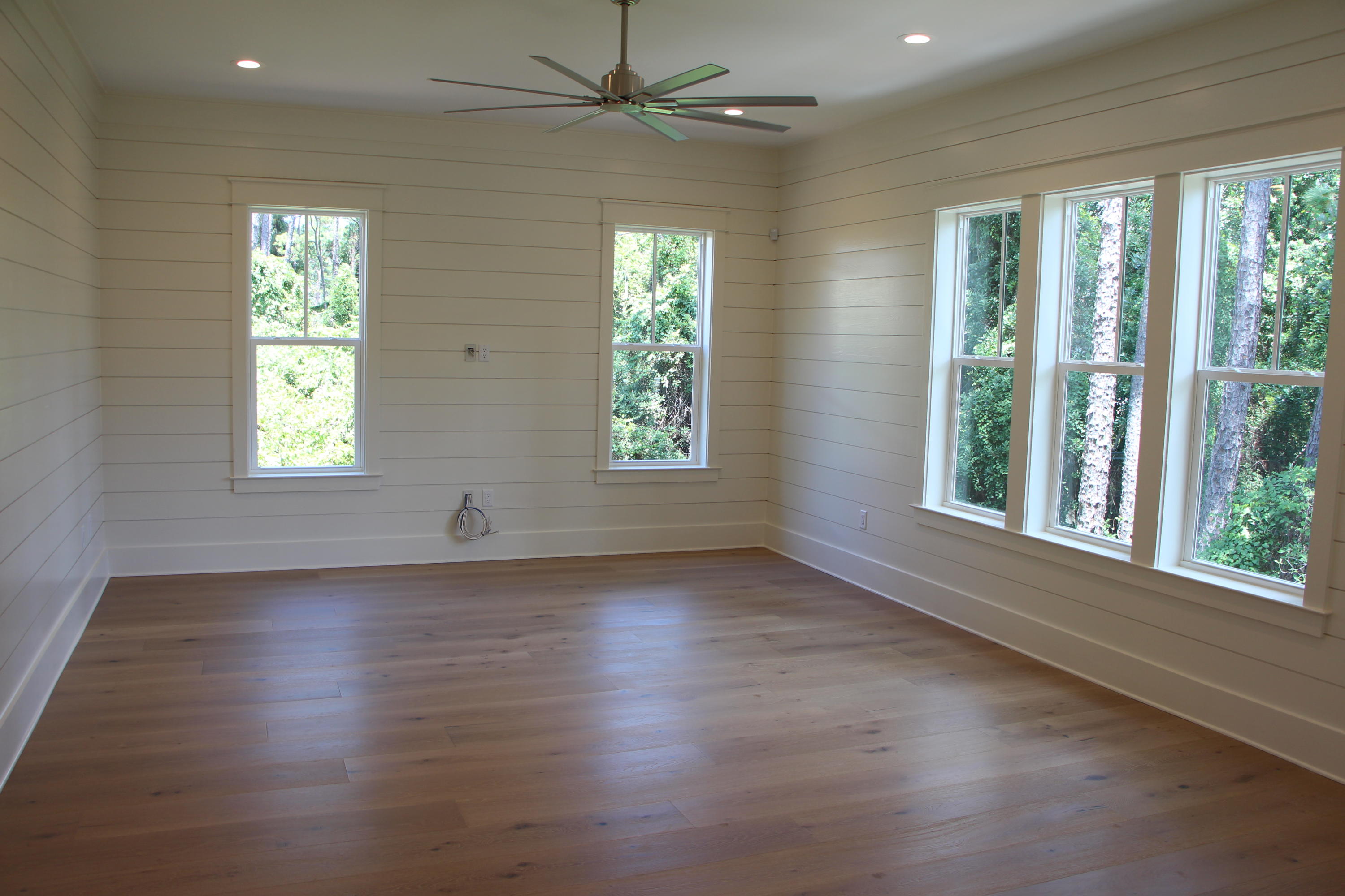 302 Cabana Trail Santa Rosa Beach, FL 32459 - Photo 3 of 8 an empty room with wooden floor chandelier fan and windows