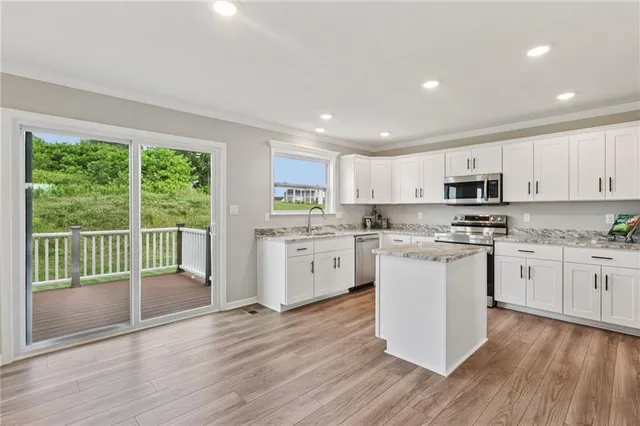 a kitchen with granite countertop white cabinets and white appliances with wooden floor