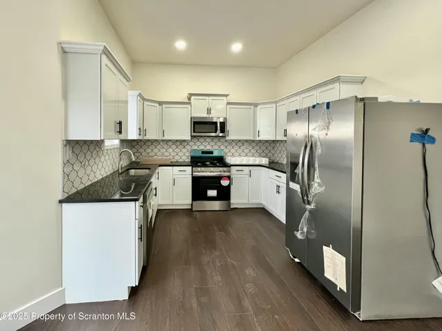a kitchen with stainless steel appliances granite countertop a refrigerator a stove and a sink