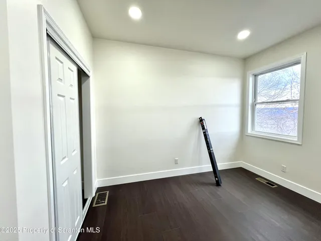 an empty room with wooden floor and a window
