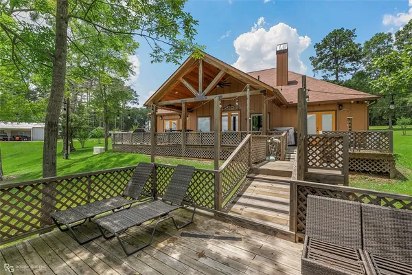 a front view of a house with wooden fence and large trees
