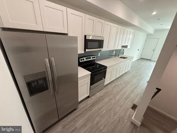 a kitchen with stainless steel appliances a refrigerator a sink a stove top oven a refrigerator and cabinets