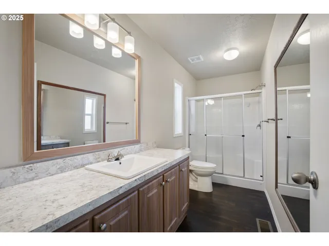 a bathroom with a granite countertop sink a toilet and a mirror