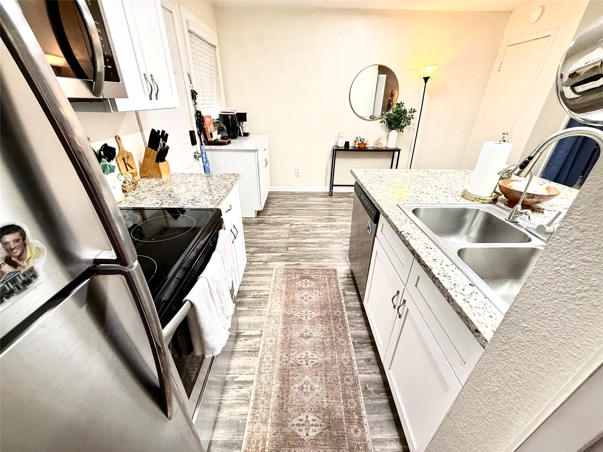 2413 Leon Street, Unit 108 Austin, TX 78705 - Photo 4 of 22 Kitchen with white cabinetry, light wood-style floors, appliances with stainless steel finishes, and light stone countertops