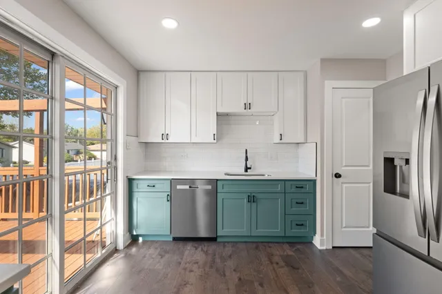 a kitchen with stainless steel appliances granite countertop a refrigerator a sink and white cabinets with wooden floors