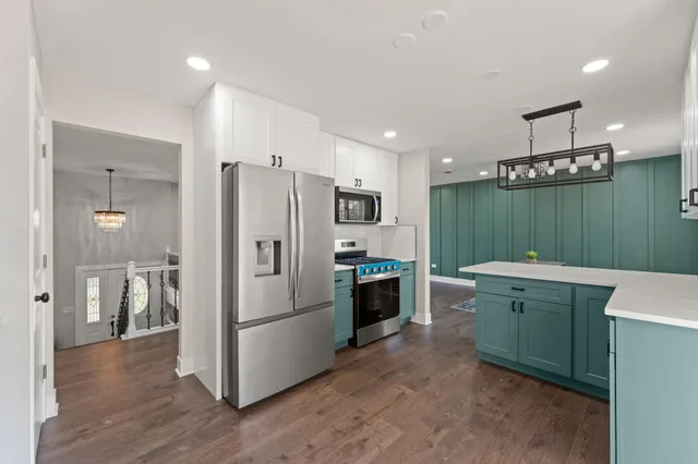 a kitchen with kitchen island stainless steel appliances a refrigerator a sink a stove a microwave and island