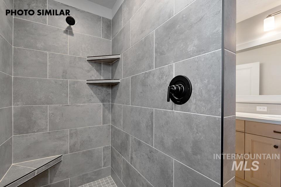 1644 Haystack Emmett, ID 83617 - Photo 17 of 33 Shower featuring large format gray wall tile, matte black fixtures, an integrated corner bench, and two built-in corner shelves