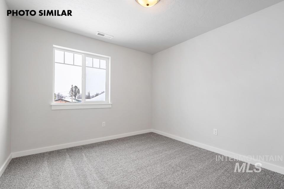 1644 Haystack Emmett, ID 83617 - Photo 27 of 33 Bright room featuring a large window with transom-style upper panes, light gray carpet, white baseboards, and a flush-mount ceiling light
