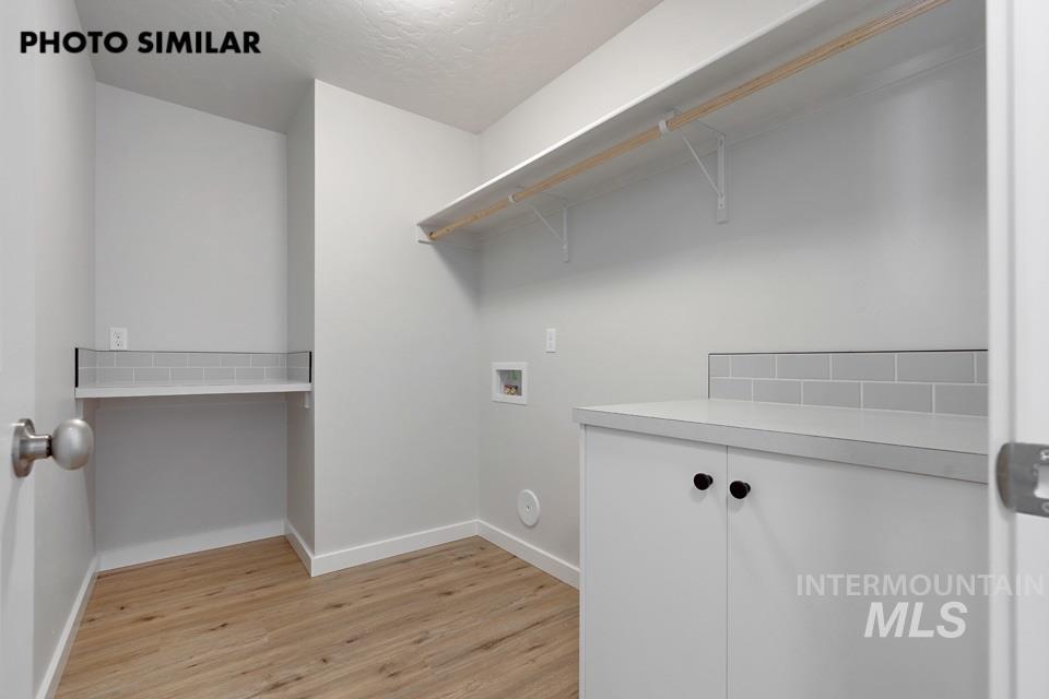 1644 Haystack Emmett, ID 83617 - Photo 31 of 33 Utility room featuring wood-finish flooring, light gray walls, and white cabinetry with dark hardware