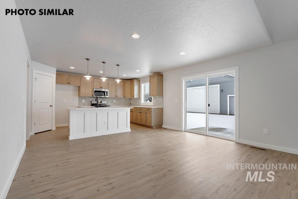 1644 Haystack Emmett, ID 83617 - Photo 8 of 33 Open-concept living space featuring wood-finish flooring, recessed lighting, and a kitchen with light wood cabinetry, a white island, and pendant lighting