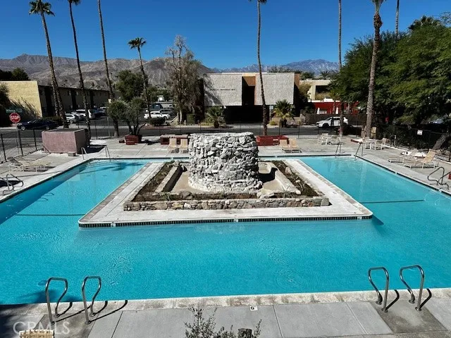 a view of a swimming pool with a table and chairs under an umbrella
