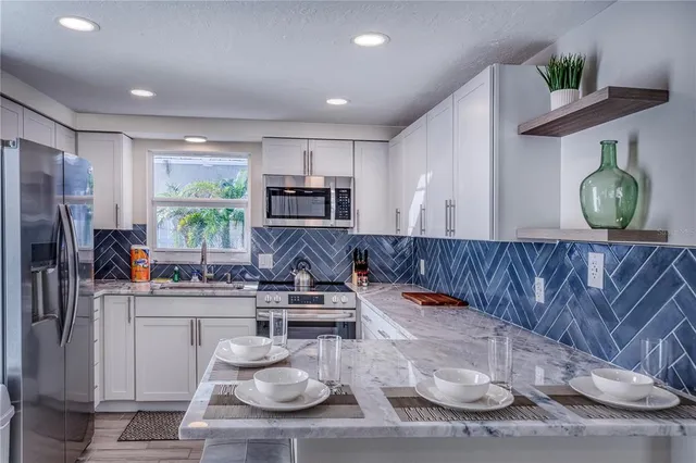 a kitchen with stainless steel appliances kitchen island granite countertop a table chairs stove and refrigerator