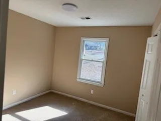 an empty room with wooden floor fireplace and windows