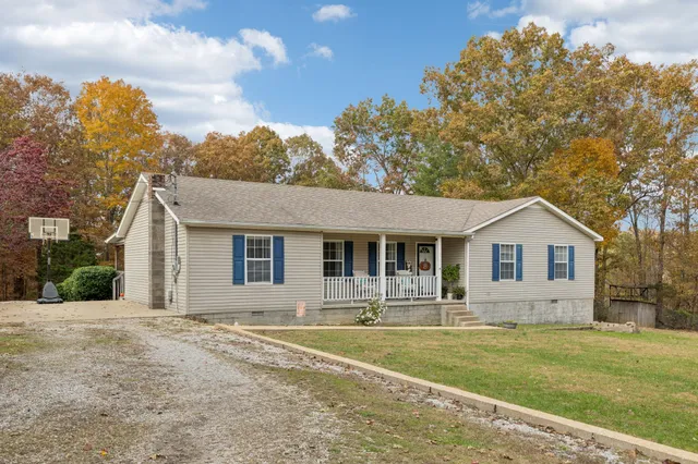 a front view of house with yard and trees in the background