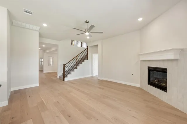 a view of an empty room with wooden floor fireplace and a window