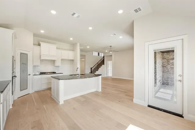 a large kitchen with stainless steel appliances kitchen island granite countertop a refrigerator and a sink