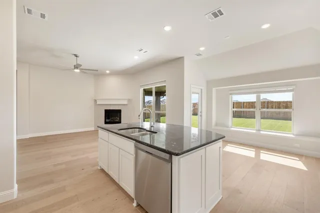 a open kitchen with granite countertop a sink and a stove with wooden floor