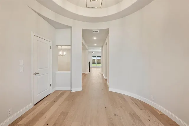 a view of a hallway with wooden floor and a bathroom