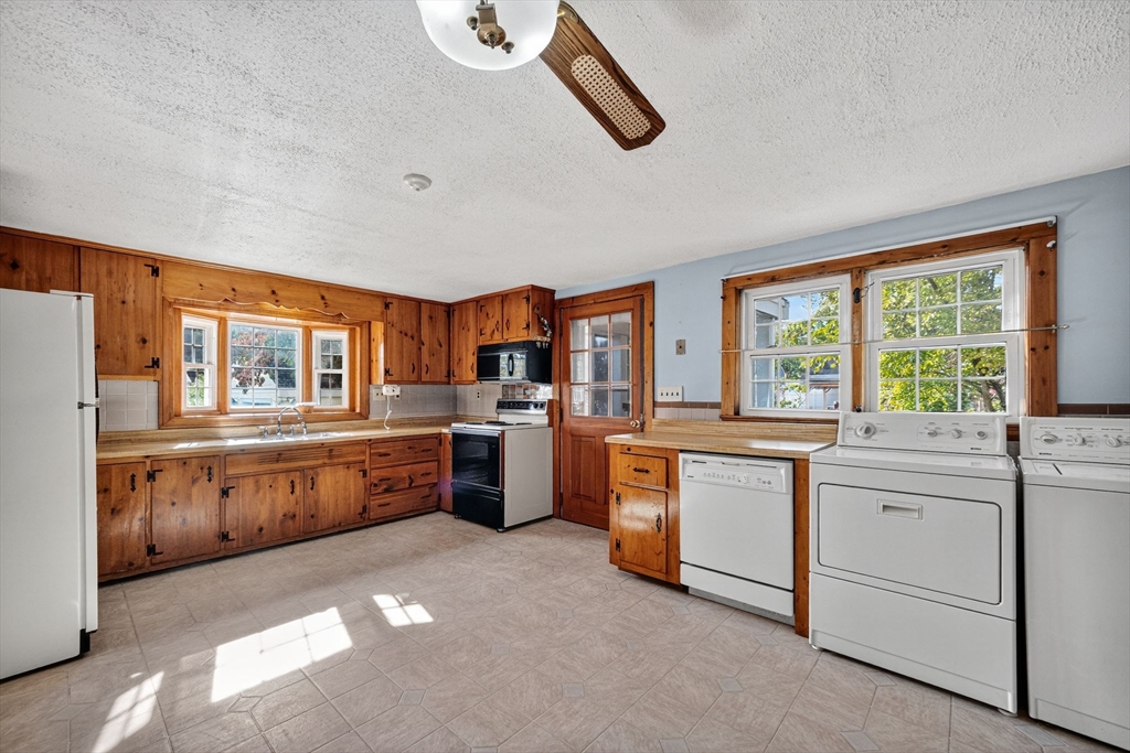 77 Whipple Road Billerica, MA 01821 - Photo 2 of 30 a large kitchen with granite countertop a large window and white cabinets