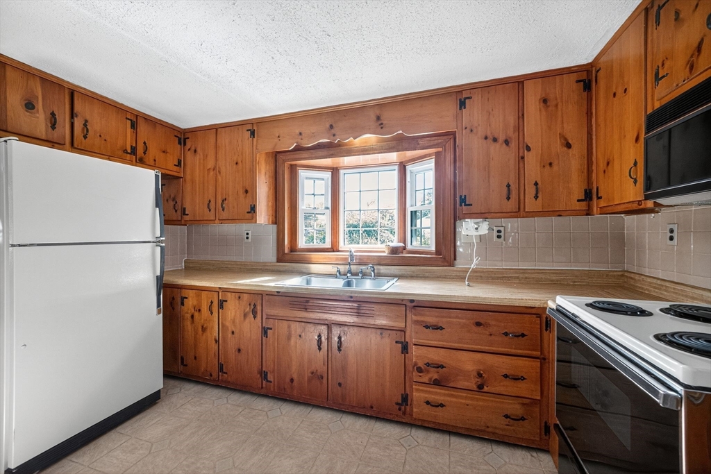 77 Whipple Road Billerica, MA 01821 - Photo 3 of 30 a kitchen with stainless steel appliances granite countertop a stove a sink and a refrigerator