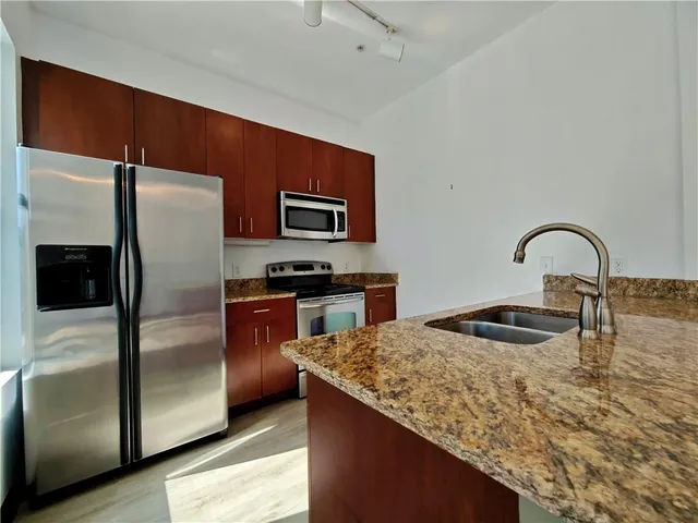 a kitchen with granite countertop a refrigerator and a sink