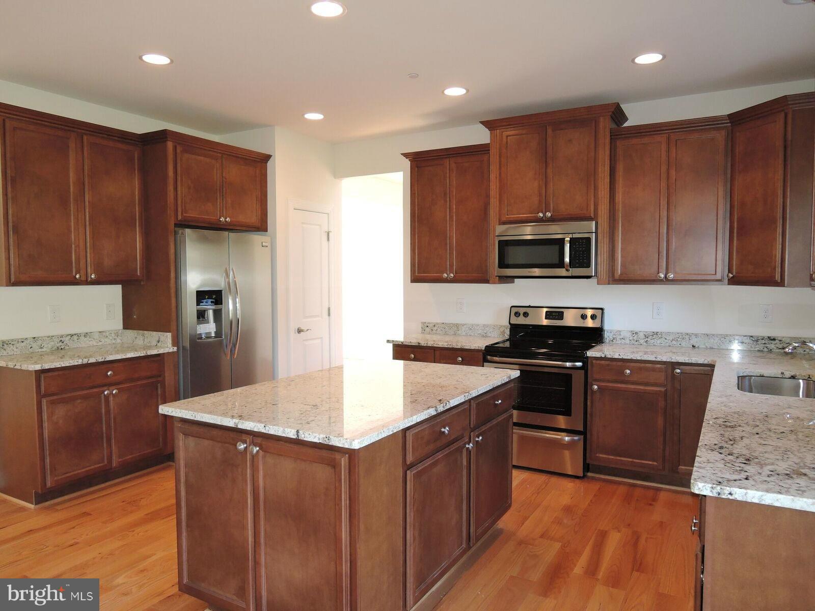 17023 Troyer Road Monkton, MD 21111 - Photo 9 of 30 a kitchen with kitchen island granite countertop wooden cabinets and a stove top oven