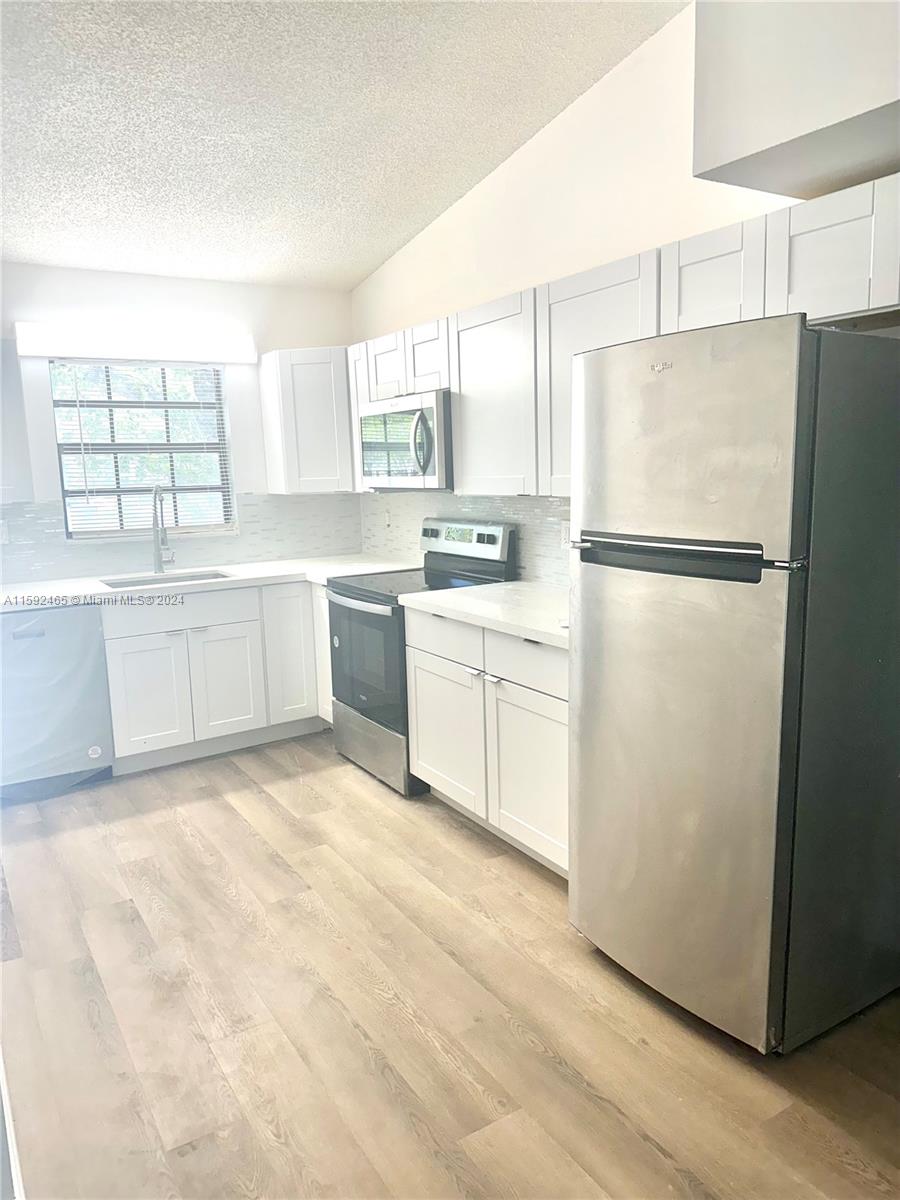 a kitchen with white cabinets and white stainless steel appliances