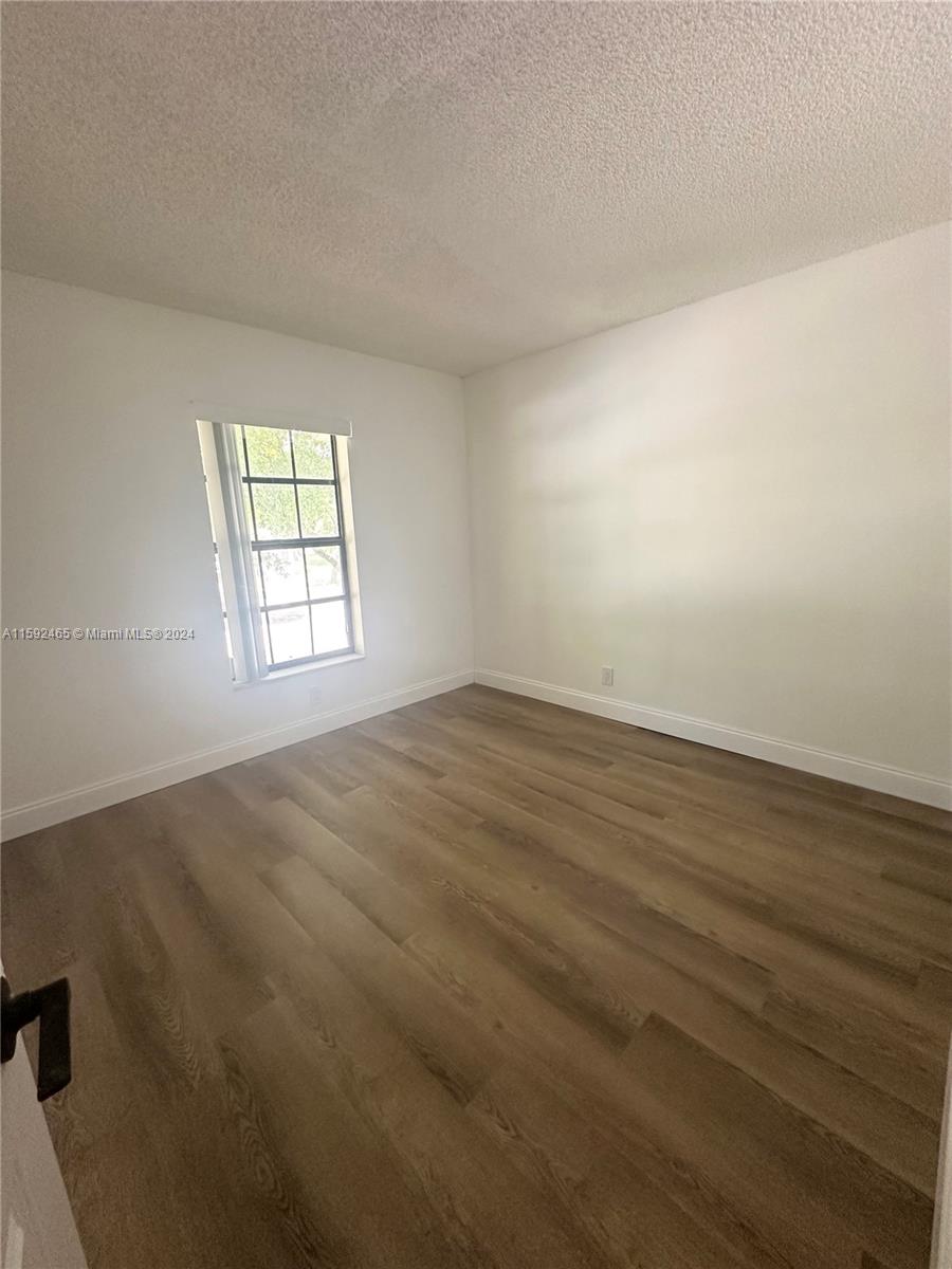 301 Olivewood Place, Unit O229 Boca Raton, FL 33431 - Photo 11 of 25 an empty room with wooden floor and windows