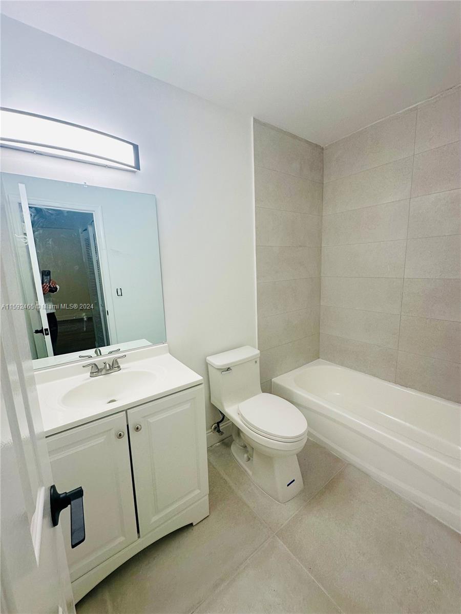 301 Olivewood Place, Unit O229 Boca Raton, FL 33431 - Photo 12 of 25 a bathroom with a white toilet sitting next to a bathroom sink and a tub