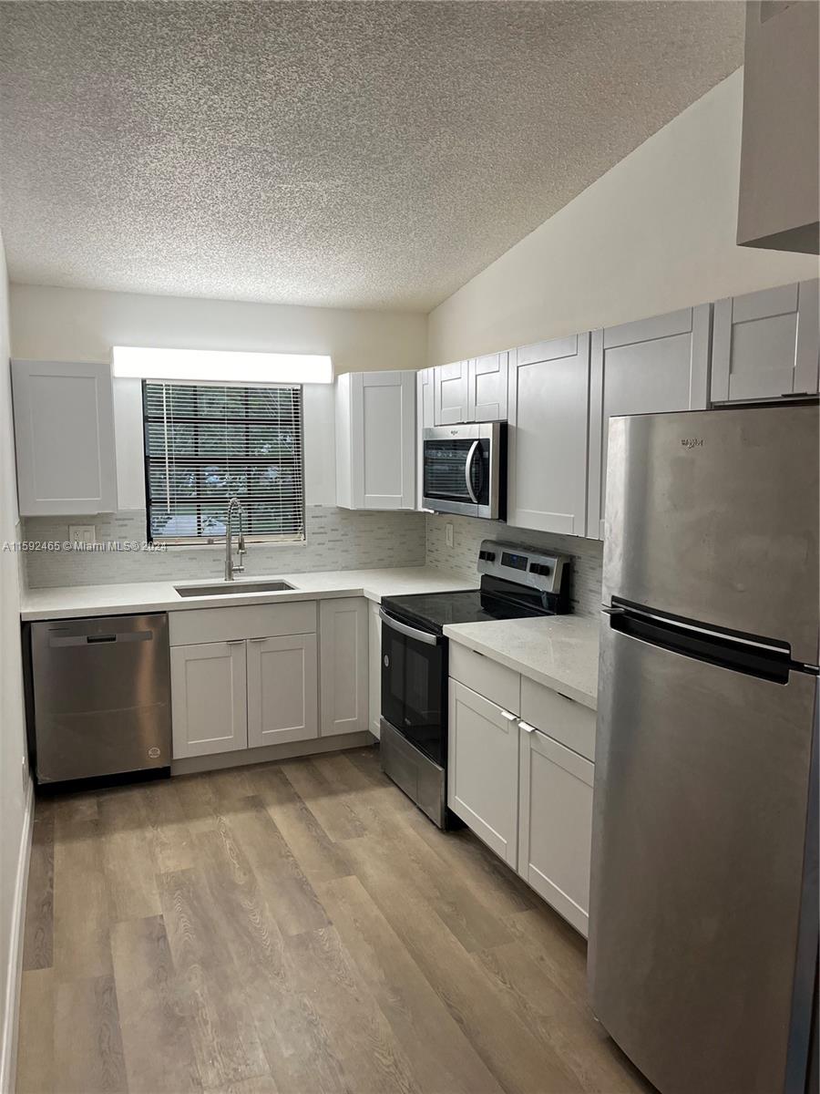 301 Olivewood Place, Unit O229 Boca Raton, FL 33431 - Photo 25 of 25 a kitchen with a white refrigerator cabinets a sink and a stove