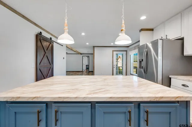 a room with kitchen island a refrigerator wooden floor and a sink