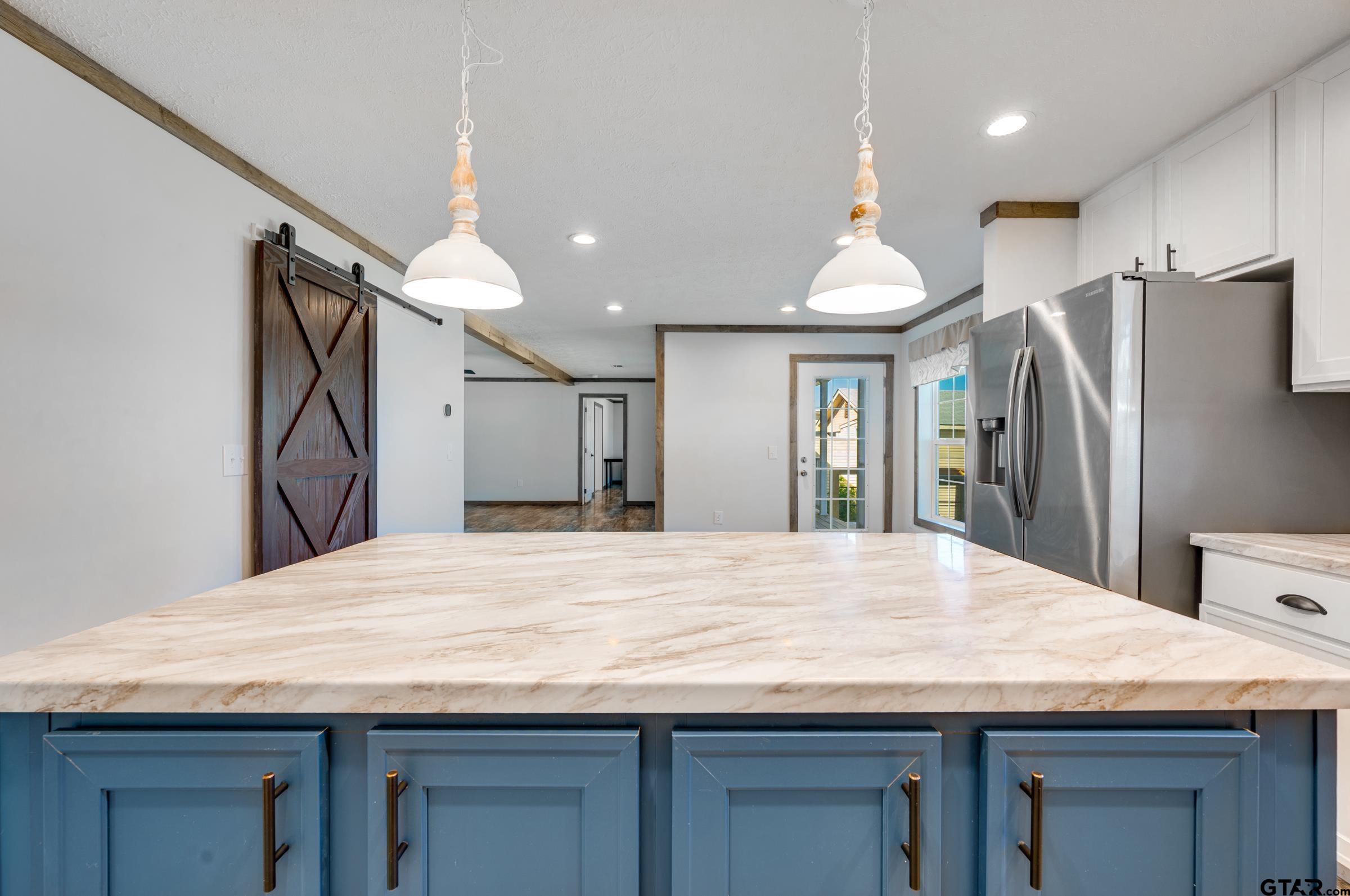 21903 Boles Road Frankston, TX 75763 - Photo 14 of 48 a room with kitchen island a refrigerator wooden floor and a sink