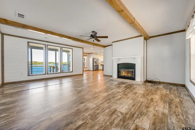 an empty room with wooden floor fireplace and windows