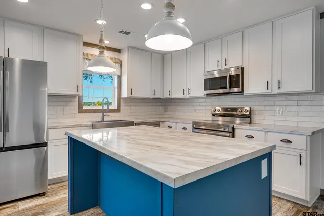 a kitchen with kitchen island granite countertop a sink stove and refrigerator