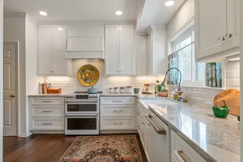 a kitchen with a sink dishwasher a stove a microwave oven with a dining table and chairs